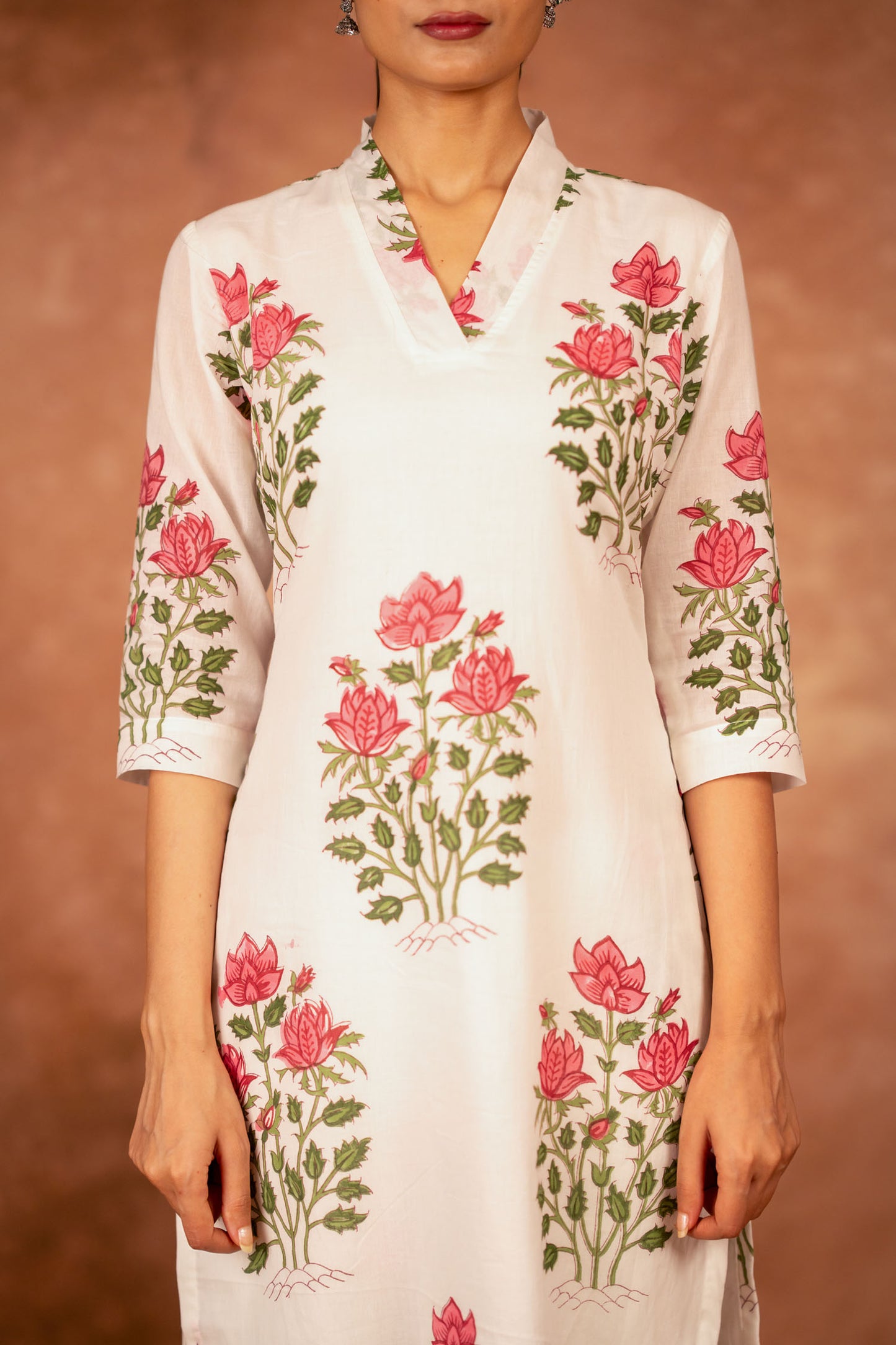 close up red green floral hand-block print on off white cotton fabric
