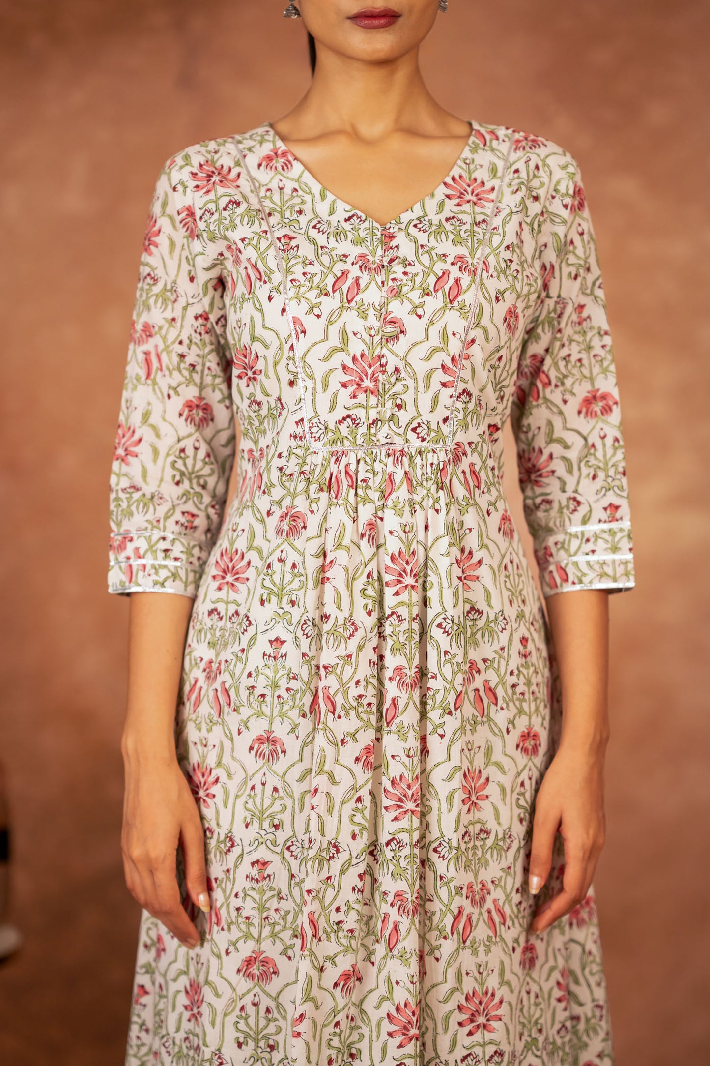close up of pink floral hand block print on green cotton fabric